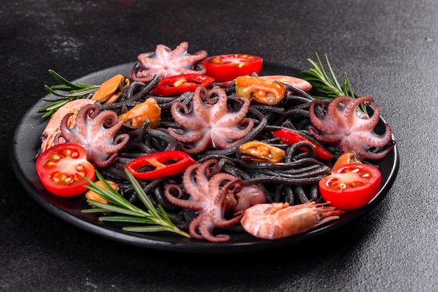 Pâtes de fruits de mer noires aux crevettes, poulpes et moules. Cuisine gastronomique méditerranéenne. Pâtes noires avec poulpe sur une plaque de pierre noire