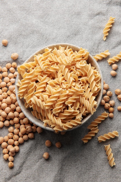 Pâtes fusilli aux pois chiches sur fond textile gris