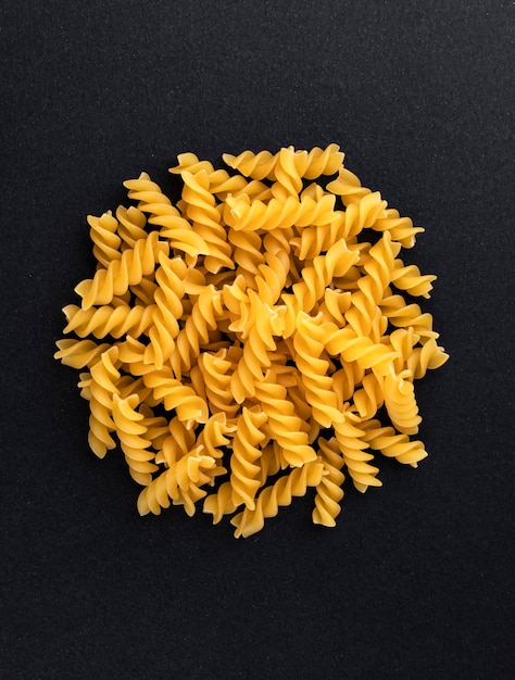 Pâtes fusilli crues isolées sur la vue de dessus de fond noir