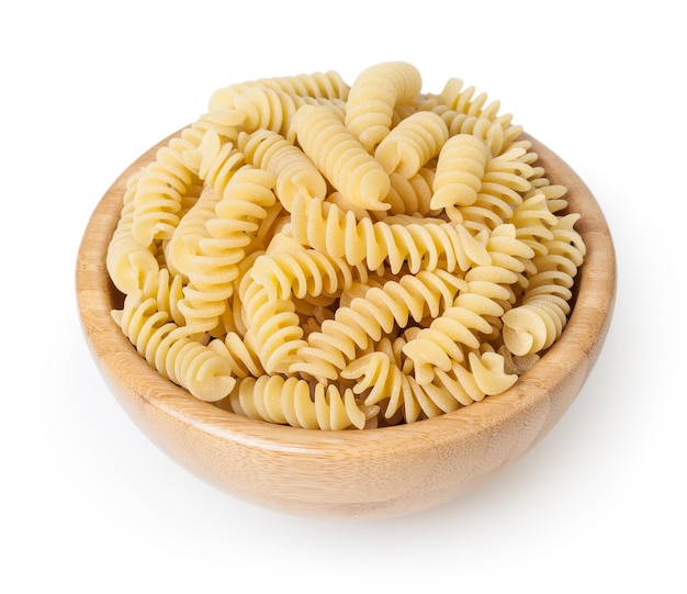 Pâtes fusilli non cuites dans un bol en bois isolé sur fond blanc avec un tracé de détourage