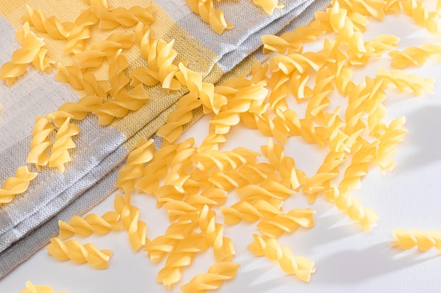 Pâtes fusilli non cuites éparpillées sur un tableau blanc