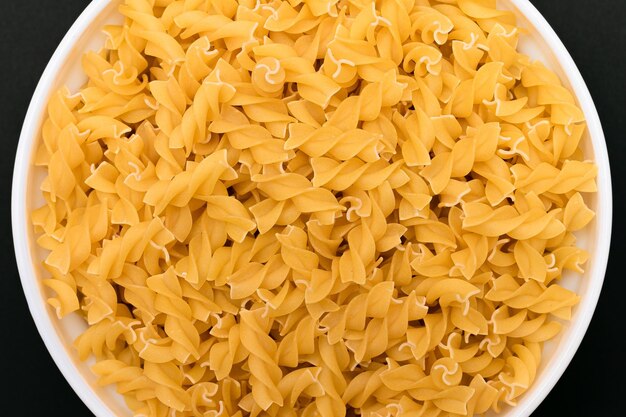 Pâtes fusilli non cuites sur plaque blanche