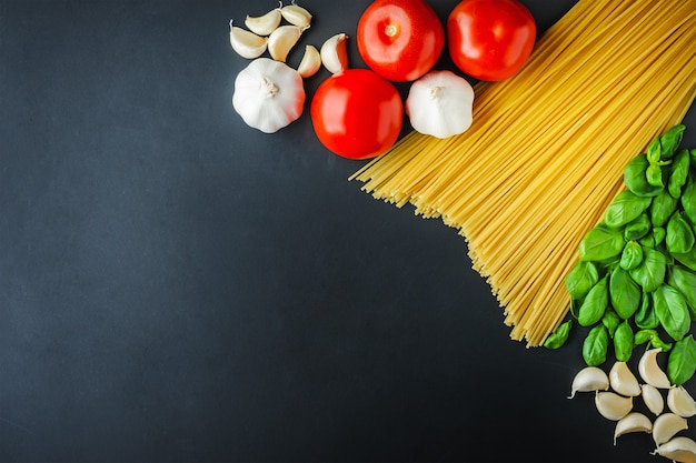 Pâtes et ingrédients pour cuisiner sur un fond sombre avec espace de copie