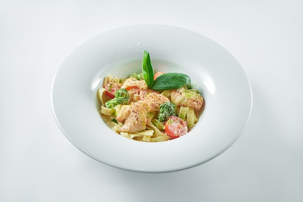 Pâtes italiennes au saumon et brocoli saupoudrées de parmesan dans une assiette blanche sur une assiette blanche. Cuisine italienne.