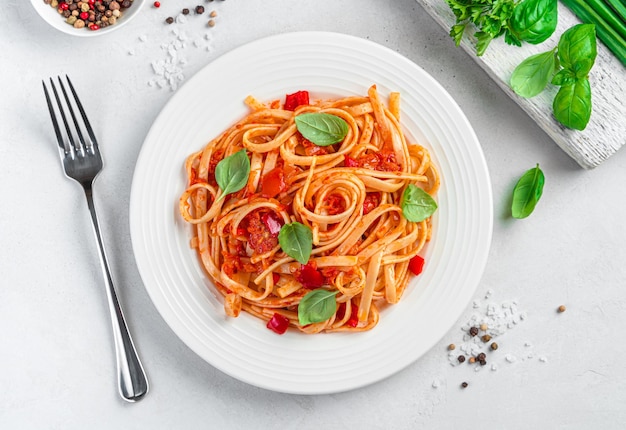 Pâtes italiennes aux tomates et basilic sur fond gris clair