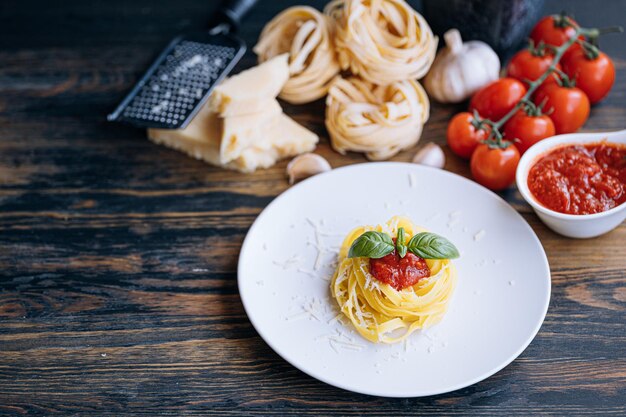 Pâtes italiennes à la bolognaise avec du parmesan râpé et des ingrédients de gros plan de basilic en arrière-plan