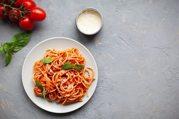 Photo pâtes italiennes classiques avec sauce tomate, parmesan au fromage et basilic sur plaque blanche