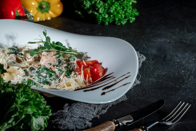 Photo pâtes italiennes faites maison avec sauce crémeuse au saumon fumé sur fond sombre