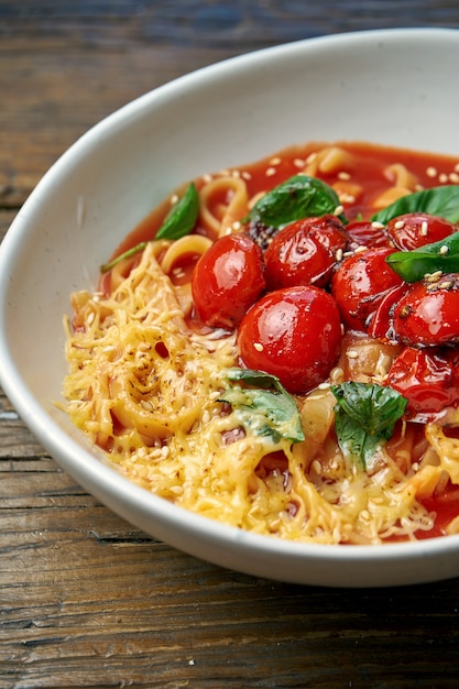 Pâtes italiennes faites maison - spaghetti aux tomates et fromage dans un bol sur un bois