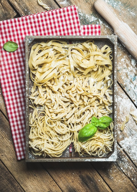 Pâtes italiennes non cuites dans un plateau en bois sur fond rustique