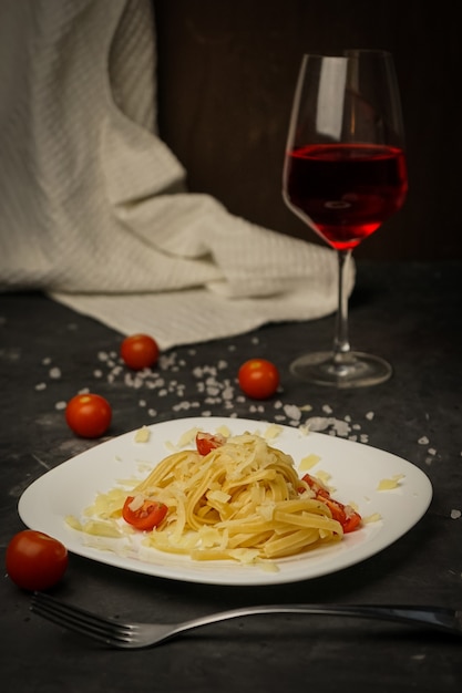 Pâtes italiennes sur une plaque sur un fond sombre avec des tomates cerises