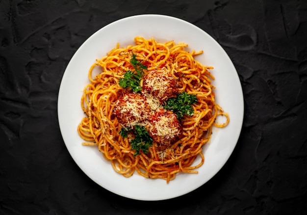 Pâtes italiennes avec sauce tomate et boulettes de viande dans une assiette avec des épices sur pierre