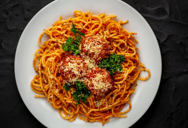 Pâtes italiennes avec sauce tomate et boulettes de viande dans une assiette avec des épices sur pierre