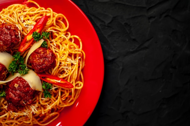 Pâtes italiennes avec sauce tomate et boulettes de viande dans une assiette avec des épices sur pierre