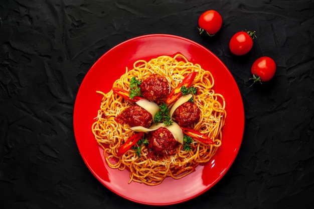 Pâtes italiennes avec sauce tomate et boulettes de viande dans une assiette avec des épices sur pierre