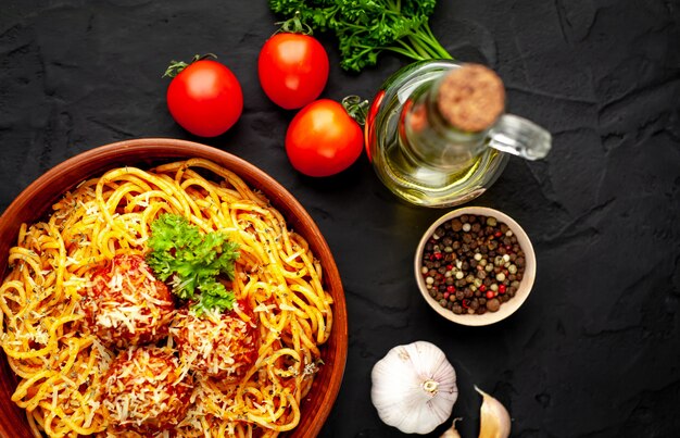 Pâtes italiennes avec sauce tomate et boulettes de viande dans une assiette sur un fond de pierre