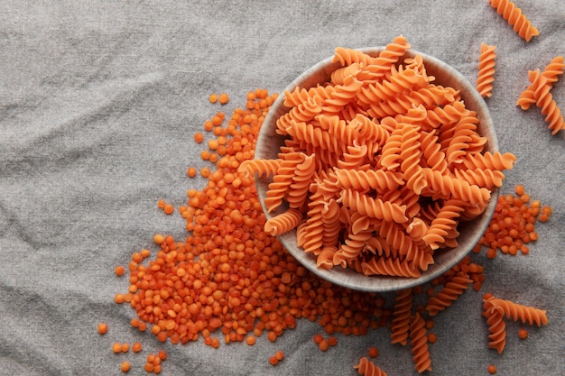 Pâtes de lentilles rouges Fusilli sur fond textile gris