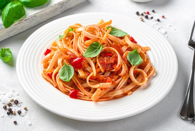 Pâtes linguini traditionnelles italiennes aux tomates poivre et basilic sur fond clair