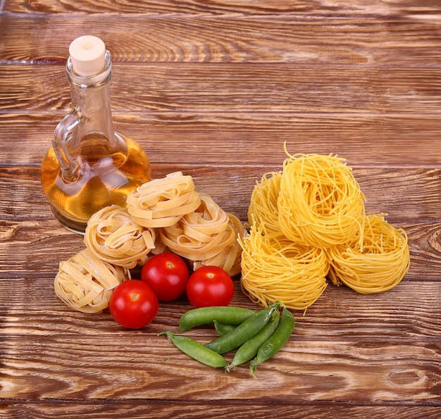 Photo pâtes sur le mur en bois avec tomate, laitue poivrée, huile d'olive et poivre.vue de dessus