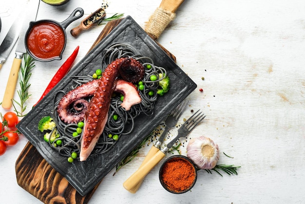 Pâtes noires aux tentacules de pieuvre sur une assiette en pierre noire Fruits de mer Vue de dessus Espace libre pour votre texte