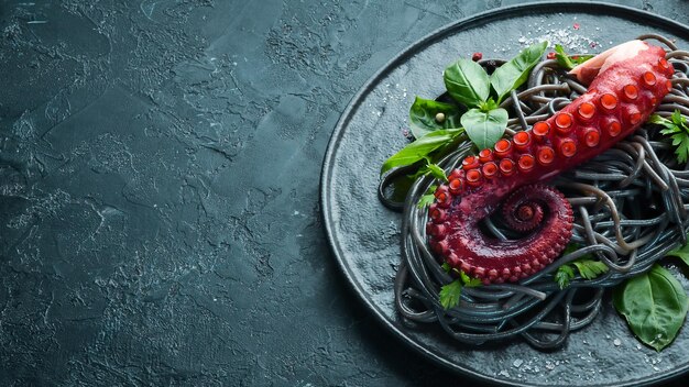 Pâtes noires aux tentacules de poulpe Fruits de mer sur une plaque de pierre Dans le vieux fond Vue de dessus Espace de copie gratuit