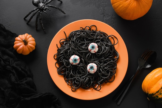 Les pâtes noires italiennes d'Halloween ont décoré les yeux d'horreur dans la plaque orange sur le noir