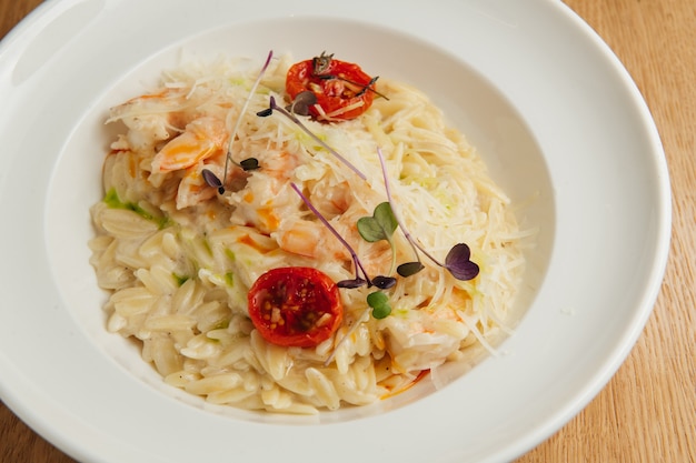 Pâtes orzo aux crevettes en assiette blanche