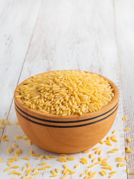 Pâtes orzo (risoni) dans un bol en bois. Vue de dessus, espace copie.