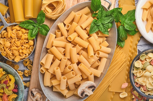 Pâtes. pâtes italiennes. Variété de pâtes italiennes traditionnelles : spaghettis colorés, tagliatelles, farfalle, penne, ptititm, nouilles, fusilli, cannelloni sur fond de vieilles pierres. Vue de dessus avec espace de copie.