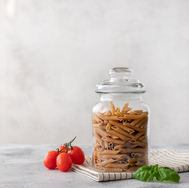 Pâtes penne au blé entier dans un récipient en verre. fermer. concept de régime