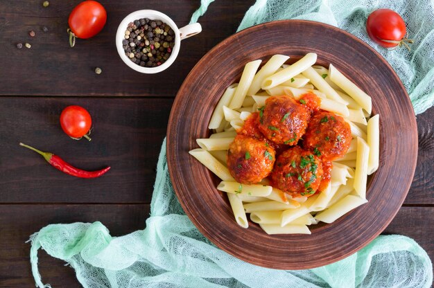 Pâtes penne aux boulettes de viande à la sauce tomate dans un bol en argile