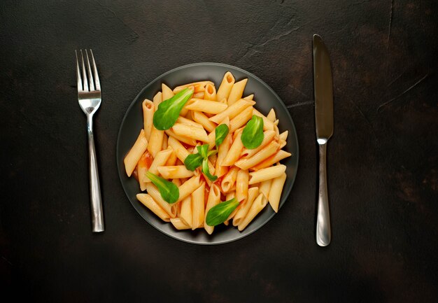 Pâtes penne dans une assiette sur un fond de béton