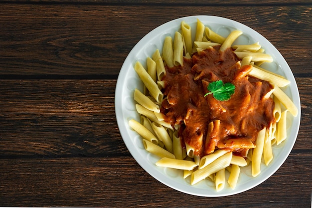 Pâtes penne italiennes typiques sur fond de bois avec sauce tomate