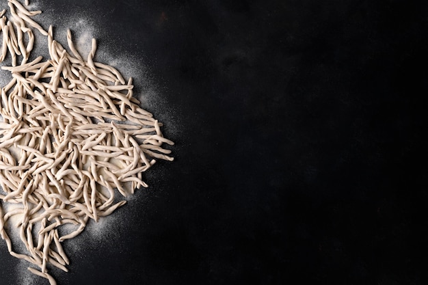 Pâtes des Pouilles de blé entier appelées Pizzarieddi ou maccaruni sur tableau noir. Fond de pâtes italiennes faites maison