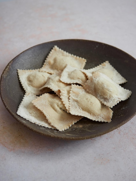 Pâtes de ravioli italiennes fraîchement préparées et cuites à la maison dans une assiette sombre