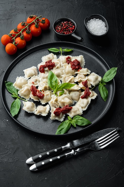 Pâtes ravioli avec sauce à la crème aux champignons et fromage - style de cuisine italienne sertie de basilic parmesan et tomate sur plaque noire, sur fond noir