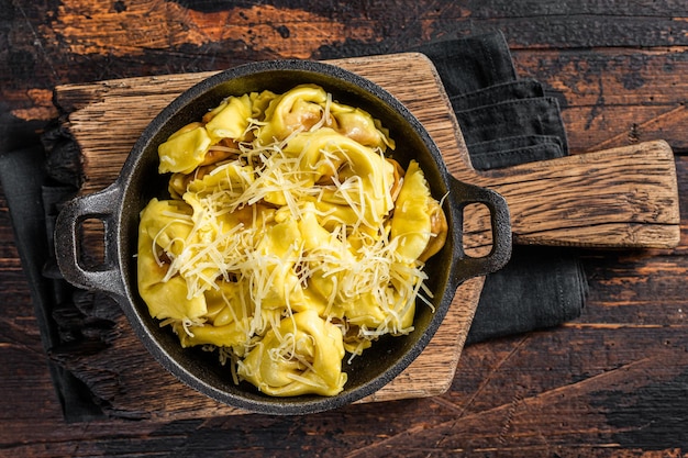 Pâtes raviolis à la mozzarella, au parmesan et à la tomate. Fond en bois. Vue de dessus.