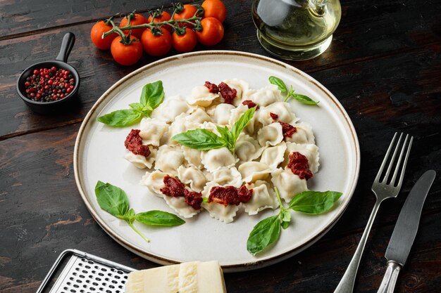 Pâtes raviolis avec sauce crème aux champignons et fromage - style de cuisine italienne sertie de basilic parmesan et tomate sur plaque blanche sur fond de table en bois foncé