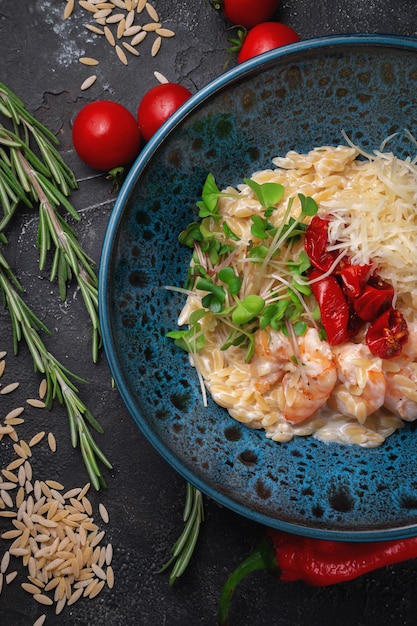 Pâtes risoni aux crevettes, piments rouges chauds sur table en pierre sombre