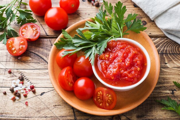 Pâtes à la sauce tomate dans un bol et tomates fraîches au persil sur une table en bois