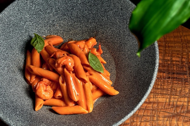 Pâtes à la sauce tomate et fromage dans une assiette sur un fond en bois