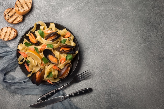 Pâtes savoureuses aux moules, calamars, persil et citron, vue de dessus.