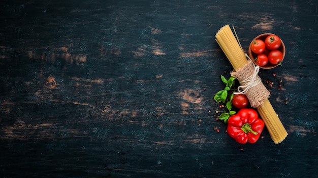 Pâtes sèches Pâtes et légumes frais Vue de dessus Sur un fond en bois noir Espace de copie gratuit