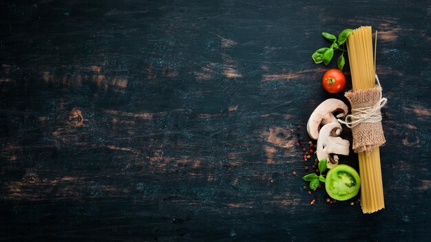 Pâtes sèches Pâtes et légumes frais Vue de dessus Sur un fond en bois noir Espace de copie gratuit