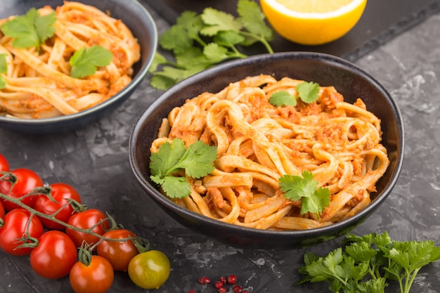 Pâtes de semoule à la sauce pesto de tomates, orange et fines herbes sur une surface en béton noir. Vue latérale, mise au point sélective