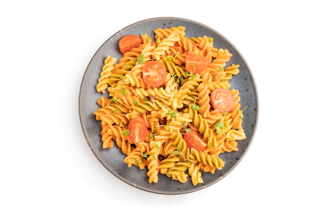 Pâtes de semoule Tortiglioni avec tomates et pousses microgreen sur tableau blanc.