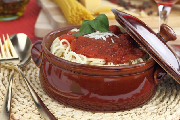 Photo pâtes spaghetti au fromage sauce tomate et basilic dans un pot en argile
