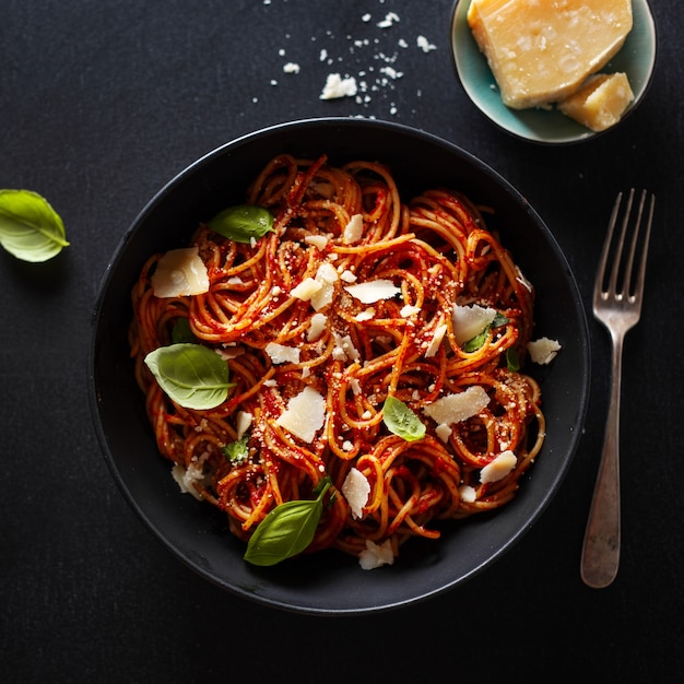 Photo pâtes spaghetti au fromage sauce tomate et basilic servies dans un bol.