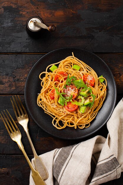 Pâtes spaghetti au pesto, avocat et tomates dans une assiette blanche rustique. Concept de nourriture végétalienne crue. Vue de dessus.