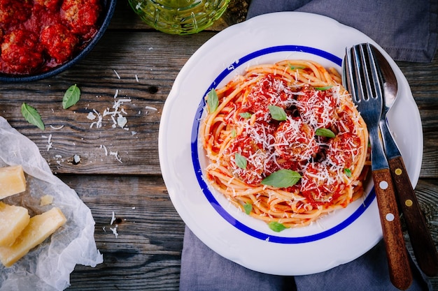 Pâtes spaghetti aux boulettes de viande sauce tomate et parmesan sur fond de bois